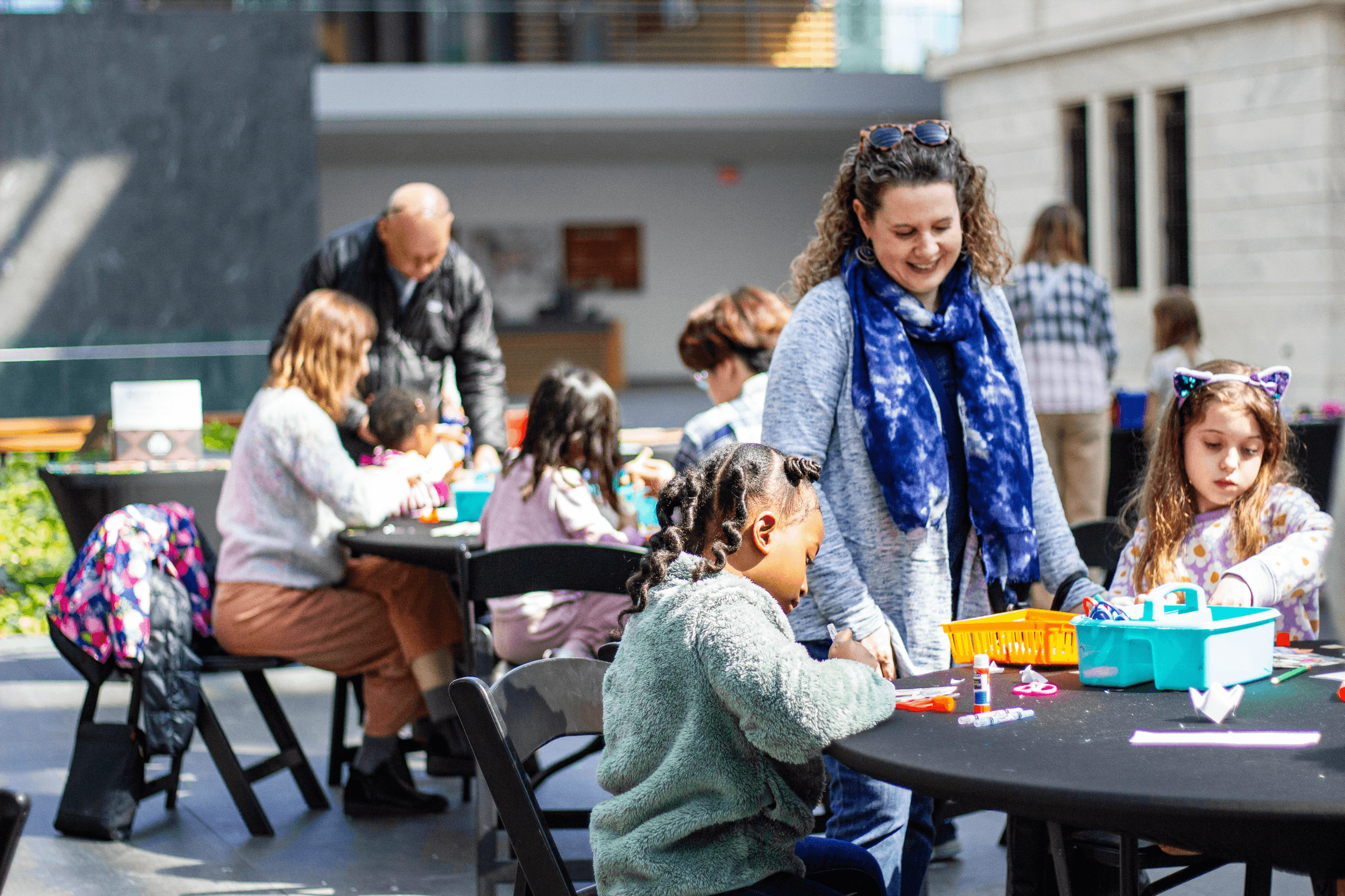 People of all ages sitting at tables making art in the atrium of the museum