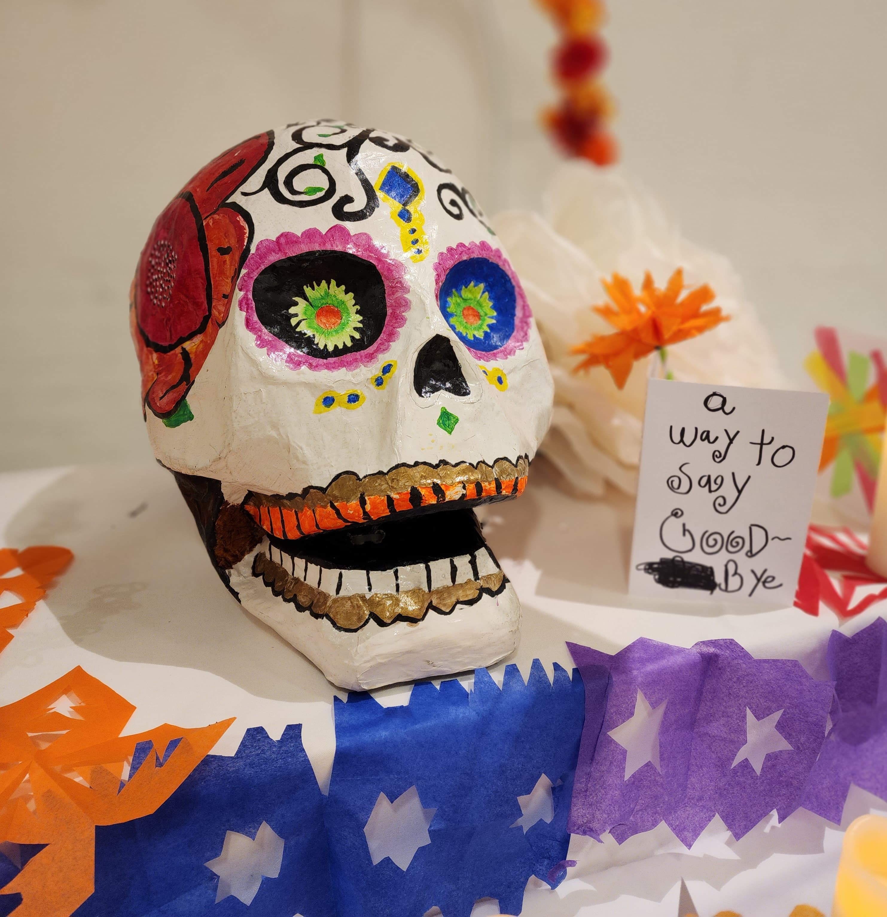 Image of a large paper mache skull surrounded by cut, colorful paper