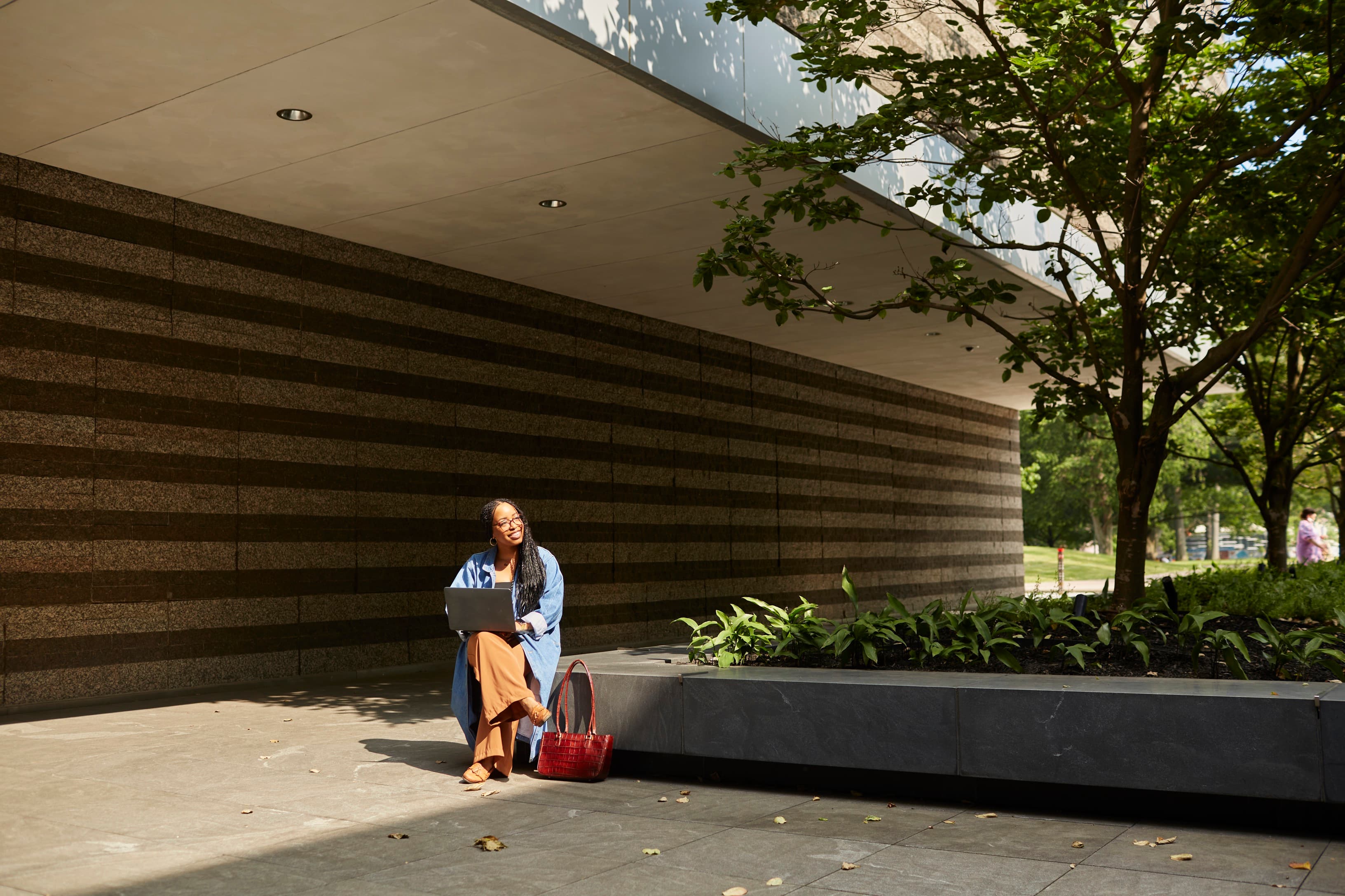 Woman sitting in the north court lobby, outside of the museum with a laptop