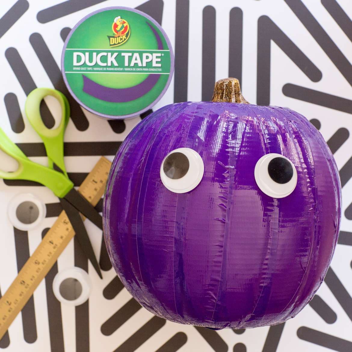 Image of a pumpkin covered in purple duct tape with large googly eyes