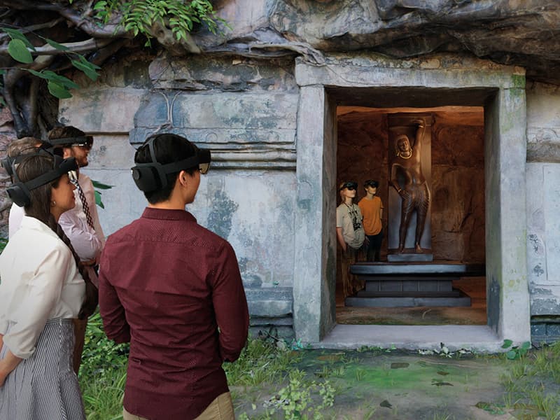 a group of people wearing HoloLens headsets look at a digital rendering of a cave